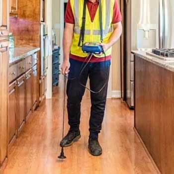 مهندس يفحص عن مكان تسرب مياه في مطبخ